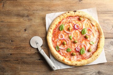 Delicious vegetarian pizza and cutter on wooden table, top view