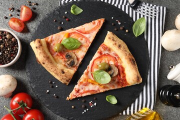 Cut delicious vegetarian pizza and ingredients on grey table, top view