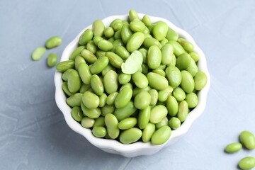 Fresh edamame soybeans in bowl on grey textured table, above view