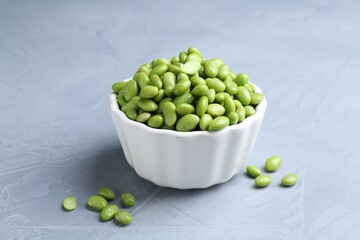 Fresh edamame soybeans in bowl on grey textured table, closeup