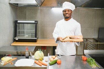 African American male chef preparing salmon fish in restaurant kitchen