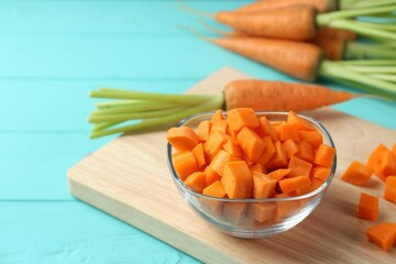 Delicious chopped carrot in bowl on light blue wooden table, closeup