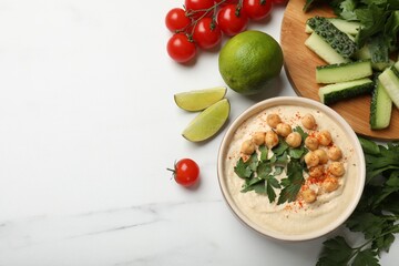 Tasty hummus with chickpeas in bowl and fresh products on light table, flat lay. Space for text