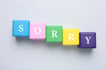 Obraz premium Word Sorry of colorful cubes with letters on light table, top view