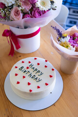 Birthday cake with the words Happy Birthday written on it, surrounded by red heart decorations.