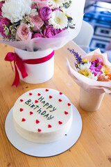 Birthday cake with the words Happy Birthday written on it, surrounded by red heart decorations.