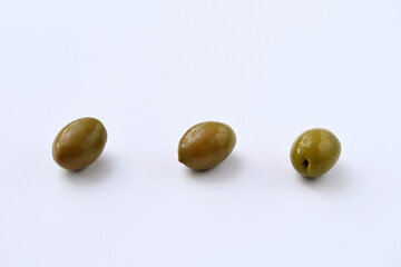 three green pickled olives on a white background