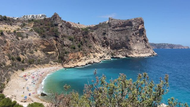 Overview on the Cala Moraig  in the Calpe area,  a stunning beach known for its crystal-clear turquoise waters, dramatic cliffs, and natural caves
