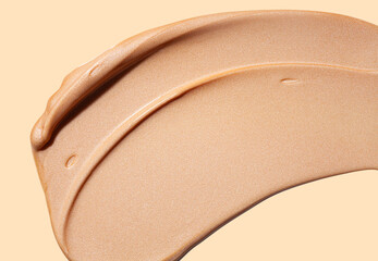 Light pink beige or glossy base liquid makeup smear of creamy luminous blusher isolated on beige...