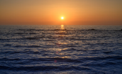 beautiful golden sunset or sunrise on a seashore bank with blue sea water and yellow sunnny evening cloudy sky