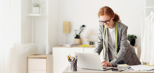 Fashion business. Confident tailor working on laptop in own dressmaking studio