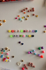 Making friendship bracelets with letter beads. Jewelry making supplies on the table. Flat lay.