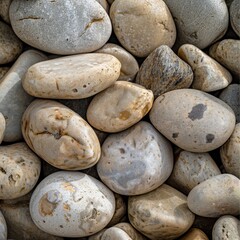 Fototapeta premium Smooth, rounded pebbles in a close-up shot. Their textured surface creates a decorative pattern. These sea stones form a unique and eye-catching background.