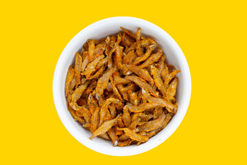 Fried anchovies in white bowl on yellow background.