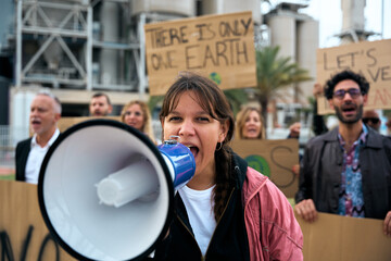 Close up portrait nonconformist gen z activist woman shouting at protest holding megaphone to group...