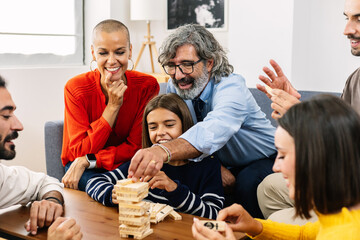 Multigenerational caucasian family having fun playing together at home, sitting together on sofa in living room.