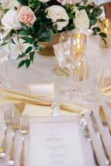 A beautifully decorated table in a restaurant with table settings and floral decorations. Luxuriously decorated table in a restaurant. Silver cutlery, flowers and clear glasses decorate the table