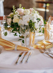 Dining table with beautiful table settings and floral decorations. Beautifully decorated table in a restaurant. Silver cutlery, fresh flowers and clear glasses decorate the table in a restaurant