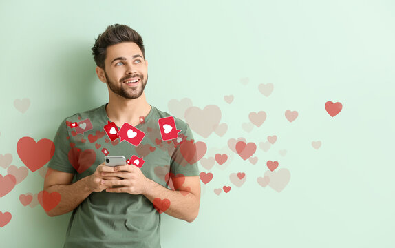 Happy young man with mobile phone on color background