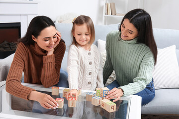 Young lesbian couple and adopted little girl playing with cubes at home