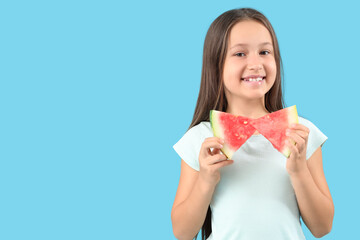 Happy little girl with slices of fresh watermelon on blue background