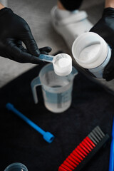 Fototapeta premium Measuring the ratio of oxygen bleach and water for cleaning furniture. Pouring dry cleaning powder into water. Effective cleaning with extractor and bleach.