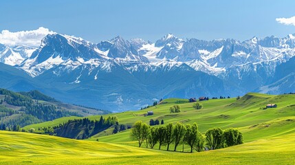 Obraz premium Majestic panoramic mountain view with fresh green meadows, rolling hills, and snow-capped peaks under clear blue skies.