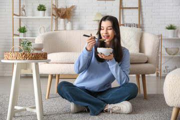 Young woman eating tasty cereal rings at home