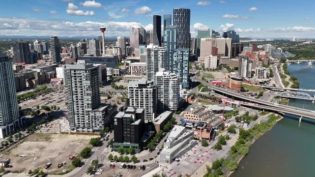 Calgary Alberta Canada, June 20 2024: High cinematic shot overlooking downtown skyline with popular landmarks and distant mountains.

