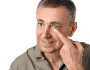 Mature man putting in contact lenses on white background