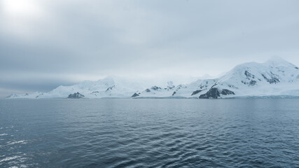 Scenic Cruising Antarctica View From Ship. Beautiful Frozen Landscape Snow Covered Mountains Cloudy Sky