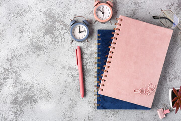 Stationery supplies and alarm clocks on grey background