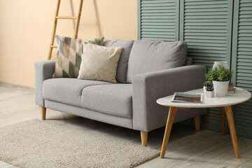 Interior of living room with grey sofa, table and folding screen
