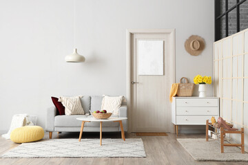 Stylish interior of hall with cozy sofa, chest of drawers and door