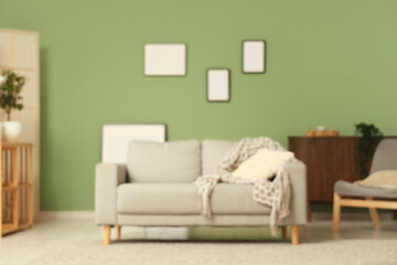 Stylish interior of modern living room with blank picture frames and comfortable sofa