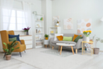 Cozy sofa, armchair and coffee table in interior of living room, blurred view