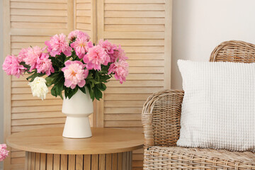 Peonies in vase on coffee table near armchair in living room