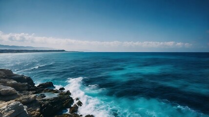 A serene coastal scene where the deep blues and turquoises of the sea meet a rugged shore, all under a vast, clear sky