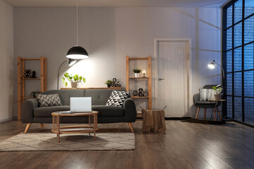 Interior of living room with comfortable sofa, table, racks and glowing lamps