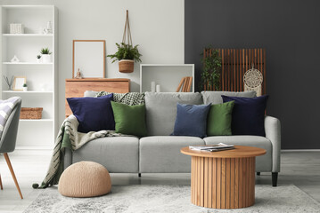 Cozy sofa with cushions and coffee table with magazine in living room