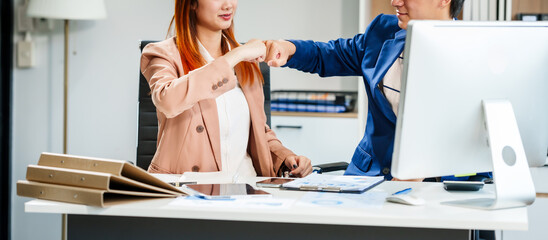 Young Asian businesswoman and businessman work together at desks, focusing on policy and planning analysis and various financial roles, emphasizing teamwork and professional collaboration.