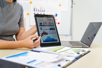 A housewife in a grey t-shirt works from home at a desk with a whiteboard, managing financial tasks...
