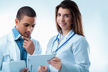 Two confident doctors discussing medical report on digital table