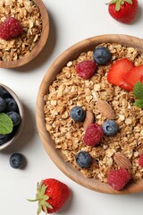 Tasty granola with berries, nuts and mint on white table, flat lay