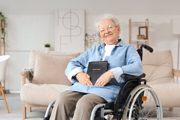 Senior woman in wheelchair with Bible at home