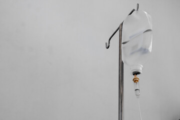 Saline bag hanging on a metal pole in hospital room, hanging bag of infused water