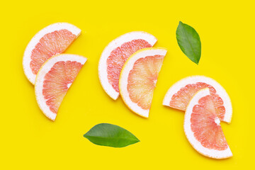 Fresh red grapefruit slices on yellow background