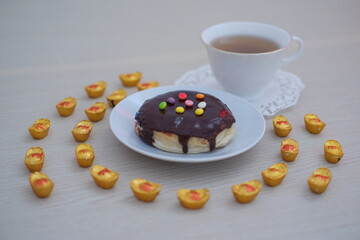 Donut with chocolate glaze and cup of tea on the table