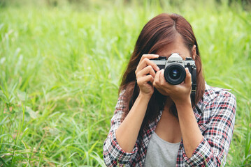 Close up hands Asian Women look at dslr digital camera vintage film style take a photo. Professional female photographer look at picture outdoor. Young woman hands shooting photo in green nature park