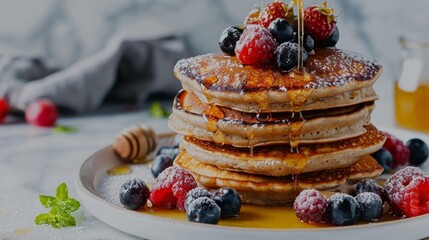 A stack of fluffy buckwheat pancakes drizzled with honey and topped with fresh berries showcasing how this ancient grain can still be a part of a delicious breakfast.
